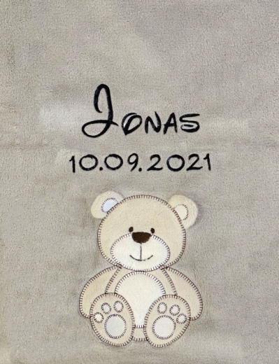 Couverture pour bébé brodée avec prénom et ours Couverture bébé grise, ultra-douillette, broderie : en haut au centre « Jonas » en lettres cursives noires, dessous date de naissance 10/09/2021. Plus bas, un ours en peluche beige aux contours marron foncé, visage souriant.