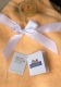 Couverture bébé orange toute douce, avec nœud en satin blanc et rose en tissu jaune clair. Deux étiquettes : Oeko-Tex Standard 100 et KiddiBaby, garantissant sécurité et confort.